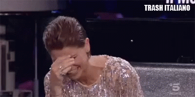 a woman in a sequined dress is covering her face with her hands .