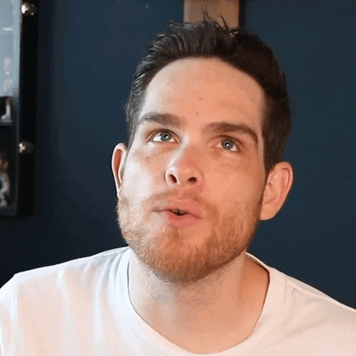 a man with a beard is wearing a white shirt and making a funny face