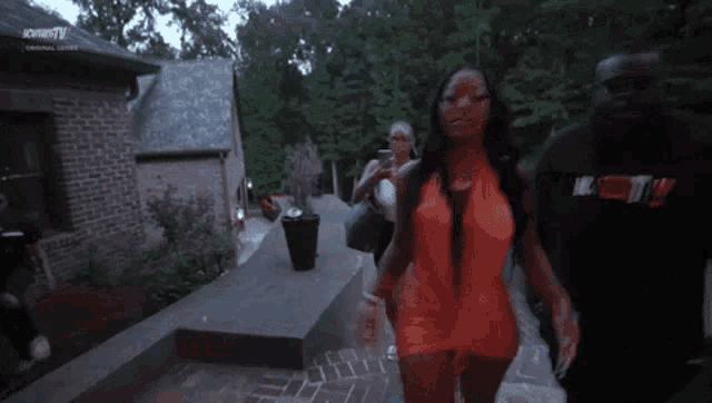 a woman in an orange dress is walking with a man in a black hoodie that says i love you !