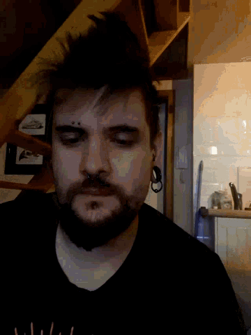 a man with a beard wearing a black shirt that says ' a ' on it