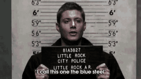 a man is holding a mug shot of himself in front of a police lineup .