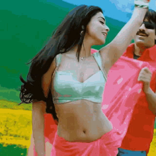 a woman in a white top and pink skirt is dancing with a man