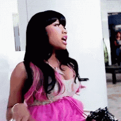 a woman in a pink dress is standing in a room with her mouth open