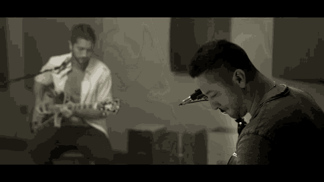 a man playing a guitar and another man playing a saxophone in a room