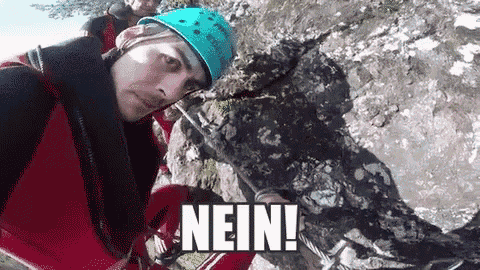 a man wearing a helmet is standing next to a rock and the word nein is above him