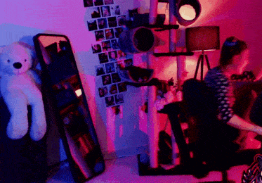 a woman sits in front of a cat tree in a room