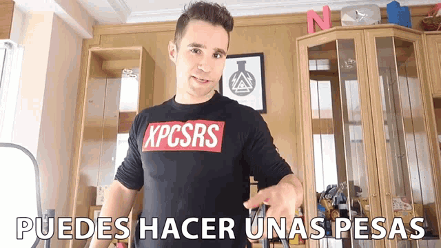 a man wearing a shirt that says kpcsrs stands in a room