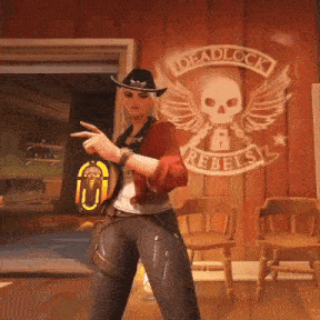 a woman in a cowboy hat is standing in front of a wall with a skull and wings painted on it .