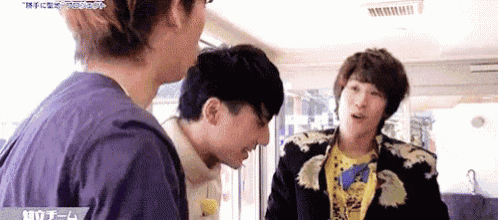 three young men are standing next to each other in a room .