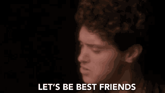a man is singing into a microphone in a dark room and saying `` let 's be best friends '' .