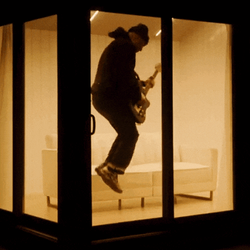 a man is playing a guitar while jumping in the air
