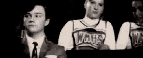 a man in a suit and tie is sitting next to a cheerleader in a cheerleader uniform .