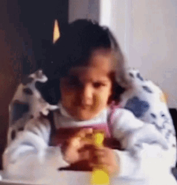 a little girl is sitting in a high chair and playing with a toy