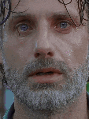 a close up of a man 's face with a beard and green eyes