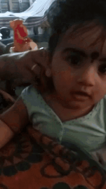 a little girl is sitting on a bed with a toy in the background