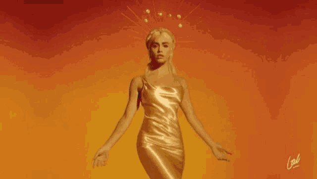a woman in a gold dress is standing in front of a red background with her arms outstretched .