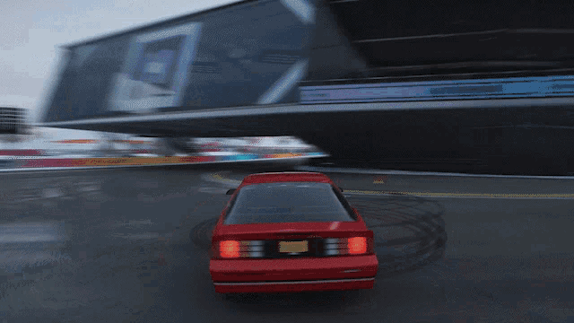 a red car is driving in front of a festival site sign