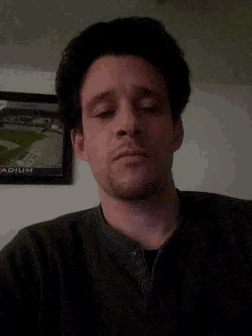 a man making a funny face in front of a framed picture that says stadium