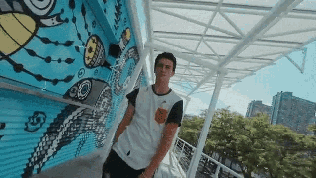 a man is standing in front of a wall with a mural on it