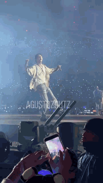a person taking a picture of a man on a stage with the name agustdzwitz on the bottom