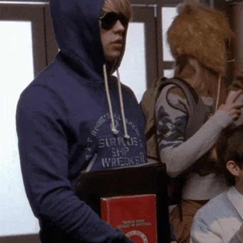a man wearing a blue hoodie that says supply ship wrecks on it