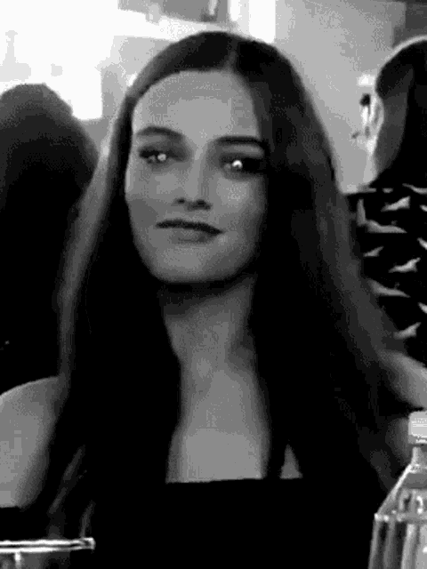 a black and white photo of a woman with long hair and a bottle of water .