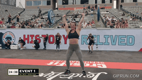 a woman is lifting a barbell in front of a sign that says history relied
