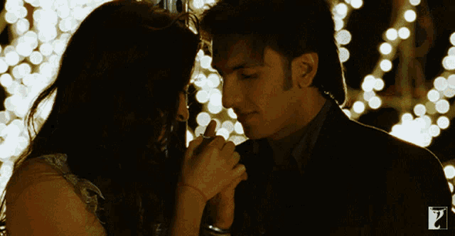 a man and a woman are touching noses in front of a sign that says ' a ' on it