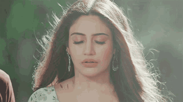 a close up of a woman with her eyes closed and her hair blowing in the wind