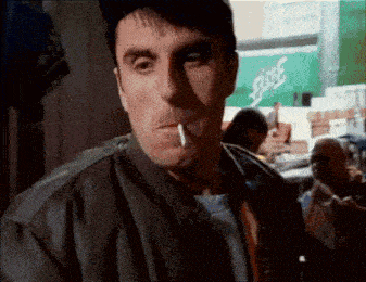 a man is smoking a cigarette in front of a green sign that says sprite