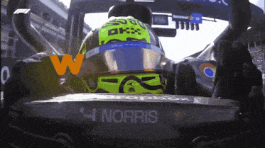 a man wearing a helmet that says okx sits in a car