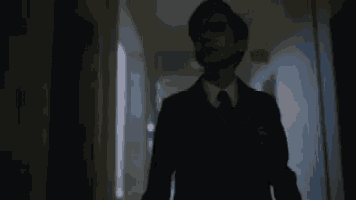 a man in a suit and tie is walking in a dark hallway .