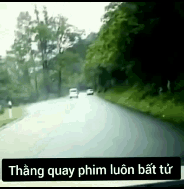 a car is driving down a road with trees on the side and the words thang quay phim luôn bất từ
