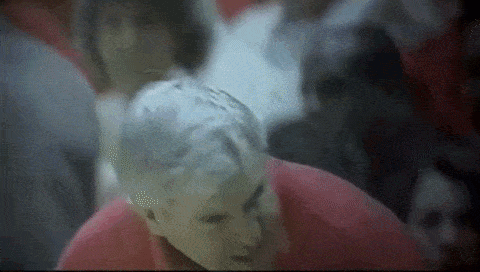 a man in a red shirt is standing in a crowd .