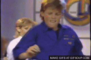 a man in a blue shirt is dancing in front of a sign that says gifsoup.com