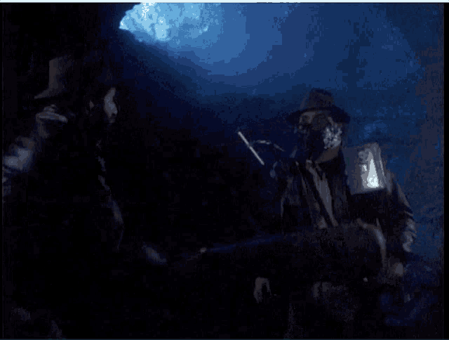 a group of people are standing in a dark room with a blue light behind them