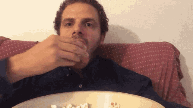 a man in a blue shirt is eating popcorn