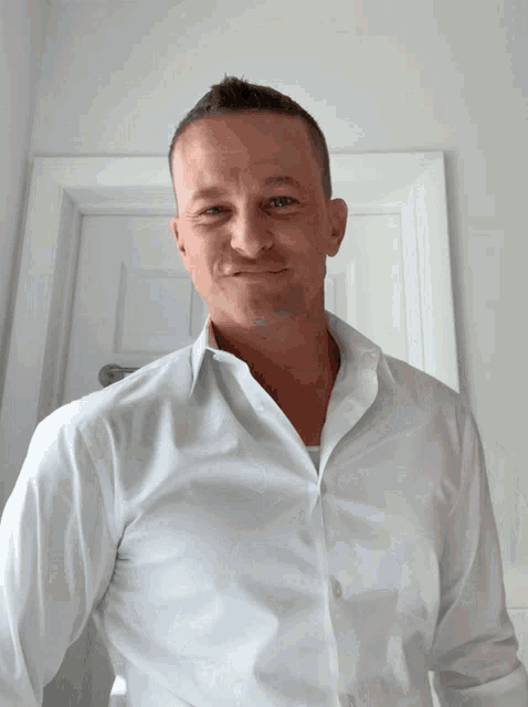 a man in a white shirt smiles for the camera