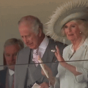 a man in a suit and tie stands next to a woman in a hat .