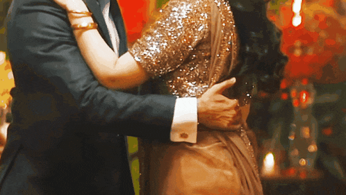 a man in a suit is hugging a woman in a gold sequined dress