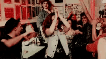 a group of people are dancing together in a room with their arms in the air .