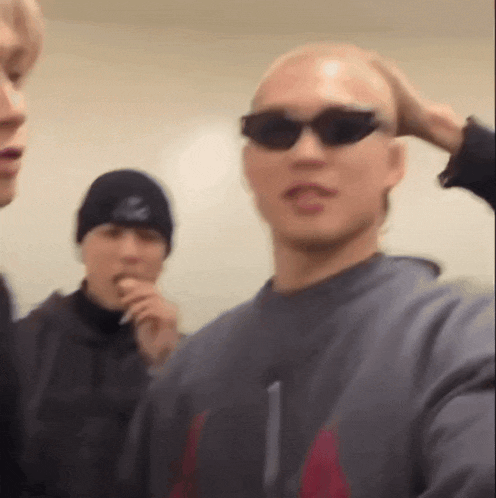 a man wearing sunglasses is taking a selfie with two other men .