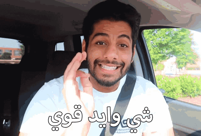 a man in a car with arabic writing on his t-shirt