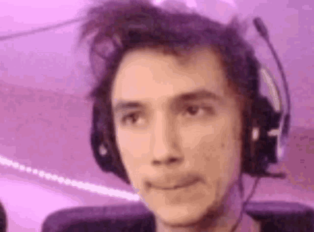 a man wearing headphones and a microphone is making a face .