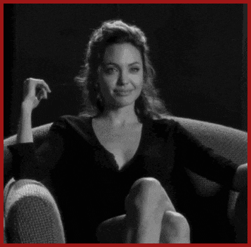 a woman in a black shirt sits in a chair with her legs crossed