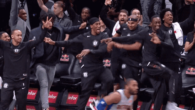 a group of basketball players are dancing in a stadium with red bull advertisements