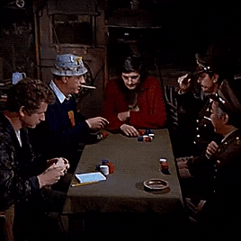 a group of men are sitting around a table with playing cards on it