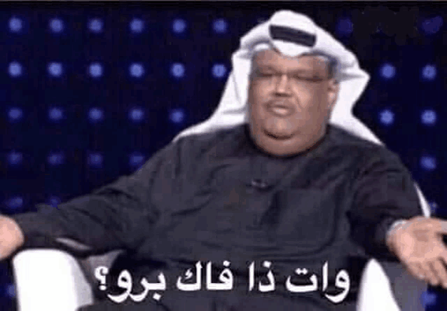 a man in a turban is sitting in a chair and making a funny face with his hands outstretched .