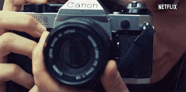 a person is holding a canon camera and taking a picture