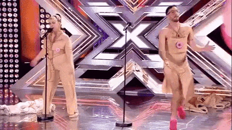 a man and a woman are singing into microphones on a stage in front of a large x .